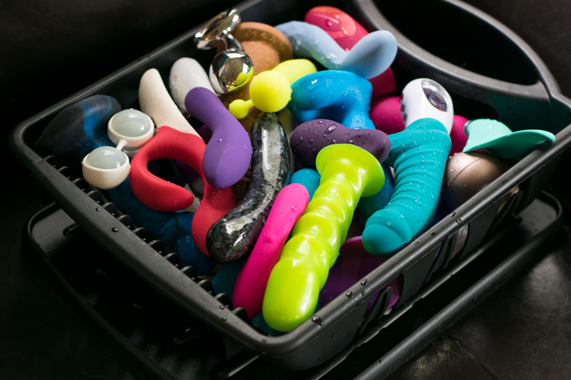 A whole bunch of sex toys piled up in a dish drying rack.