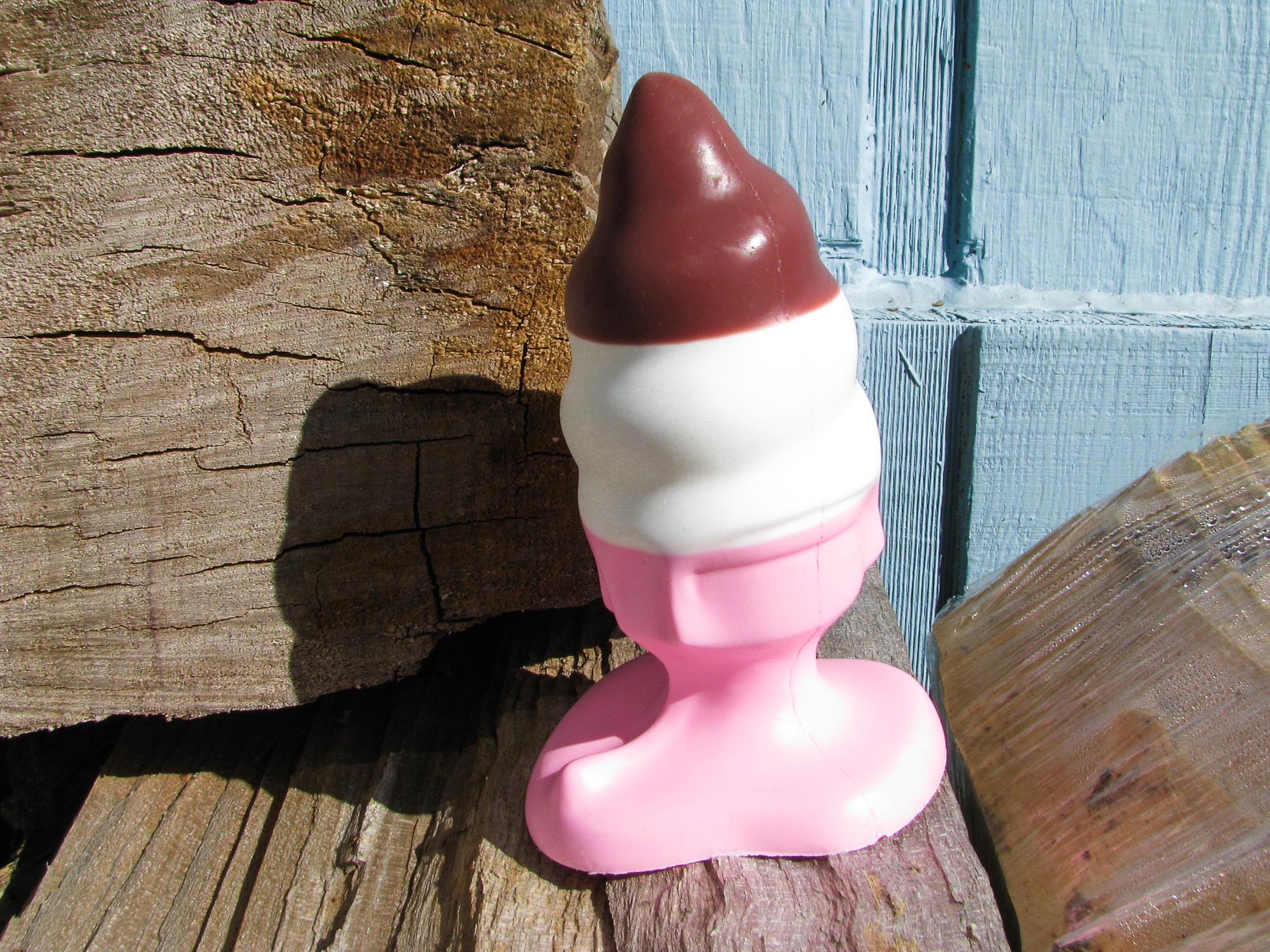 Hole Punch Toys Ass Cram Cone butt plug (which I used vaginally) standing on a wood pile in front of a pale blue house.
