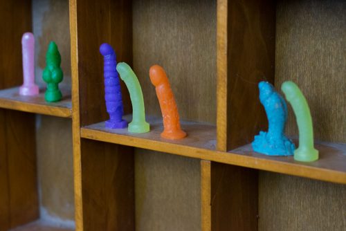 Tiny dildo mock-up photo of all the dildos on a wooden shelf. Before dusting my shelf, obviously.