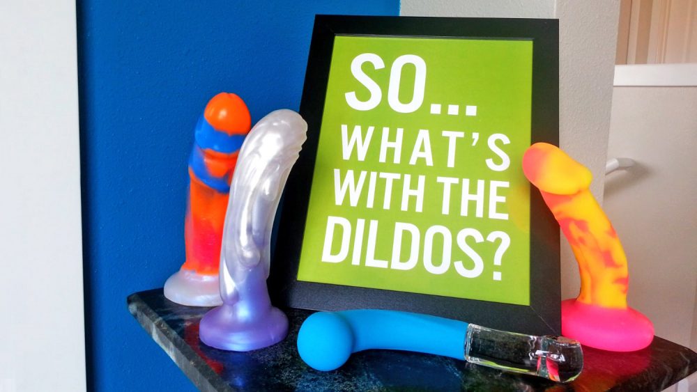 A sign reading "SO... WHAT'S WITH THE DILDOS?" surrounded by dildos.