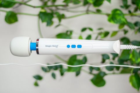 The Vibratex Magic Wand Plus corded vibrator dangling in front of a green plant.