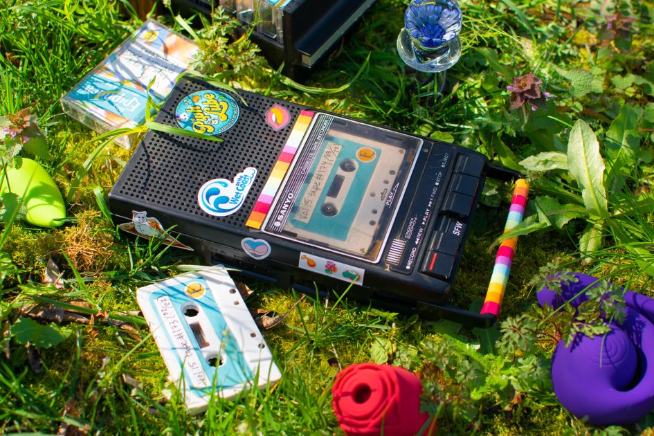 Sex blogger field notes: audio journal. Cassette player lying in the grass, surrounded by sex toys and Epiphora-labeled cassette tapes.