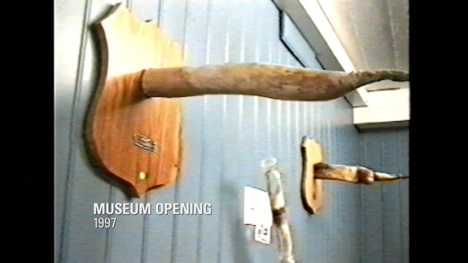 Grainy shot of the museum opening day in 1997, showing a huge phallus mounted to the wall.