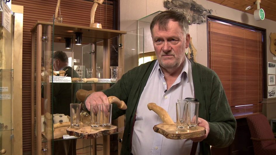 Siggi showing off some of his penis accoutrements: wooden serving trays with penises sticking out.